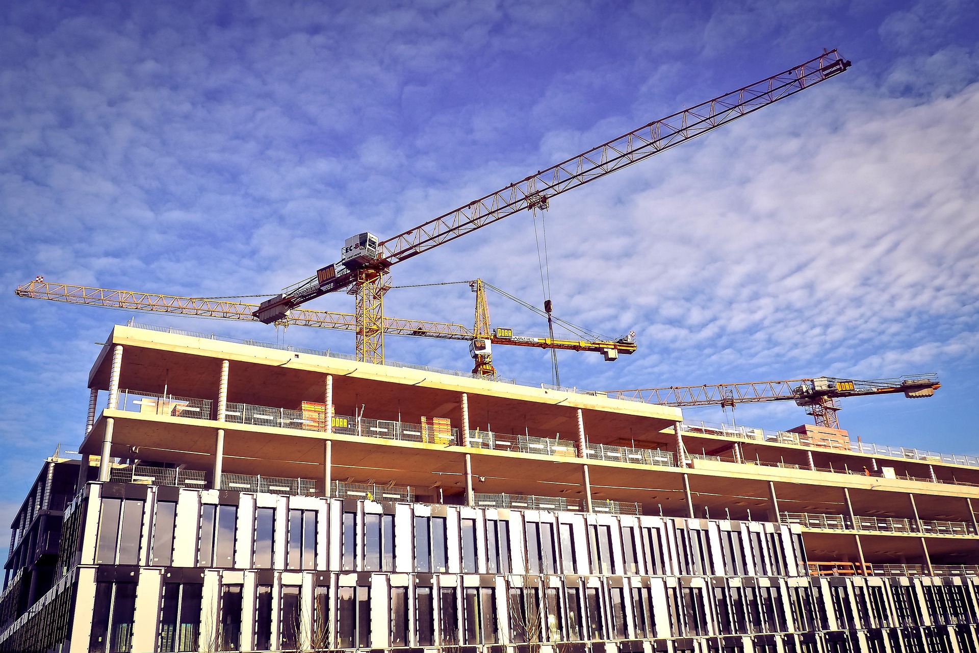 Zwei Kräne über Haus auf Baustelle